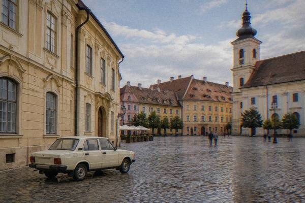 A small boxy cream saloon car of an old plain boxy shape parked on a cobbled square beside a pastel baroque palace, no badges visible, Piața Mare