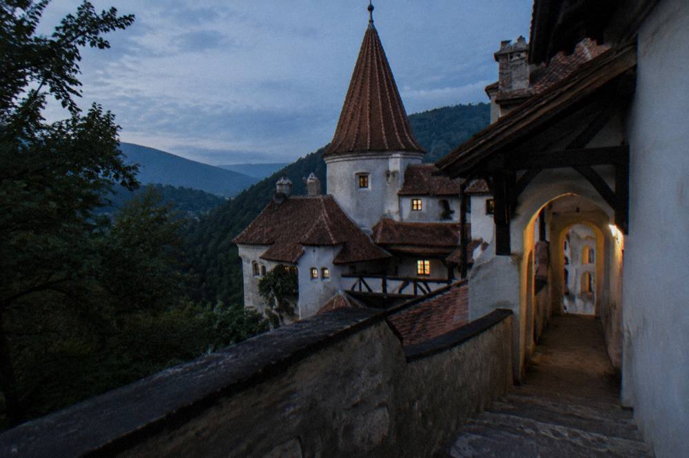 A stone staircase and arched corridor inside Bran Castle, lit by small windows