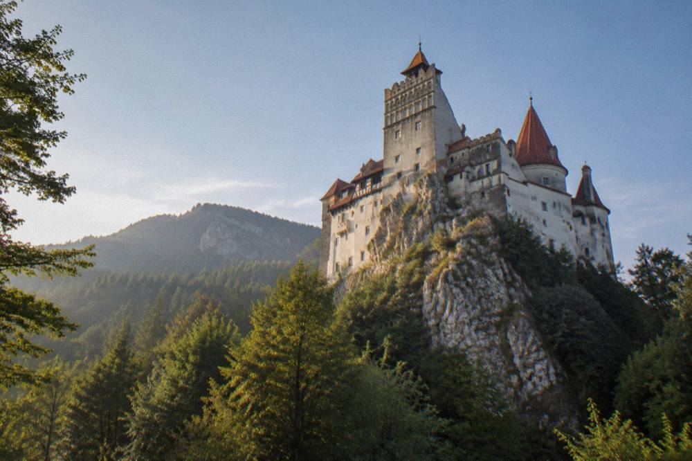 A stone fortress ruin standing on a cliff edge above a forested gorge in the Carpathian mountains