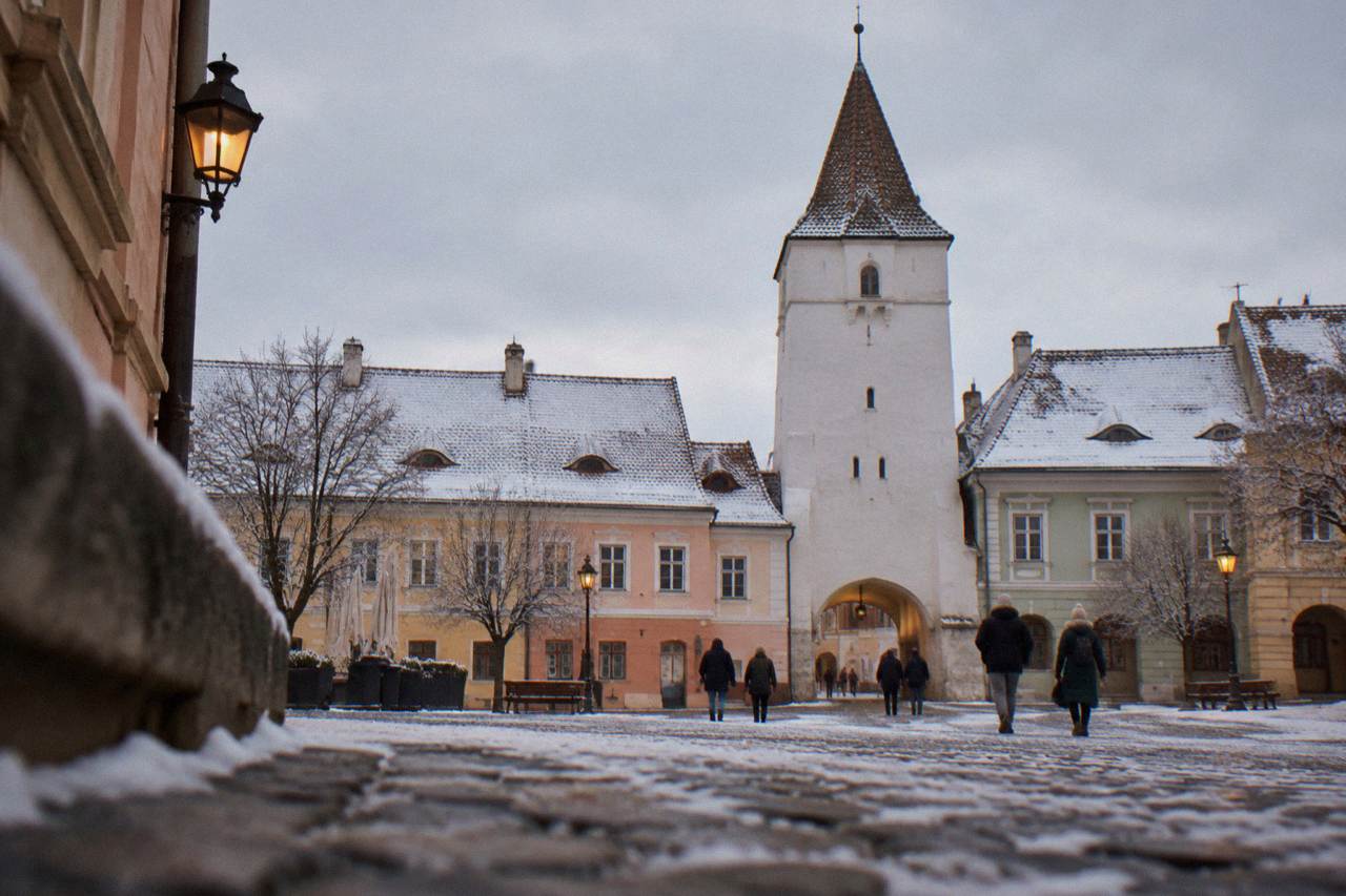 Snow-covered rooftops and the Council Tower above the coloured houses of Sibiu's old town square