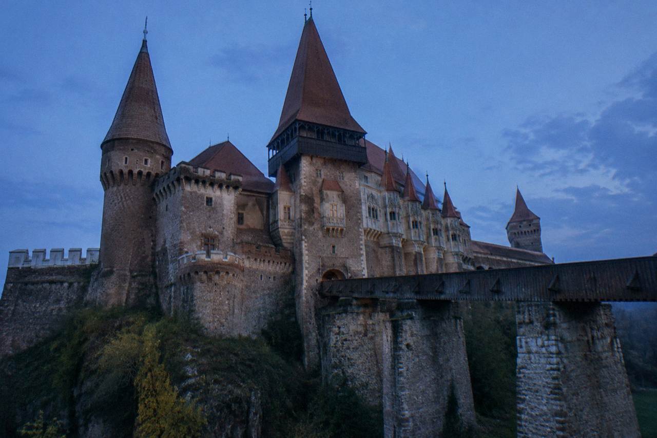 Gothic castle with tall towers and a stone bridge over a moat in Hunedoara