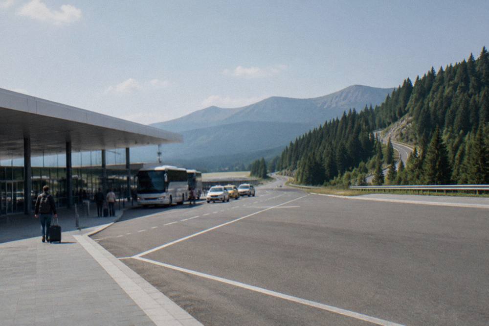 A winding mountain road climbing through pine forest toward a high alpine pass