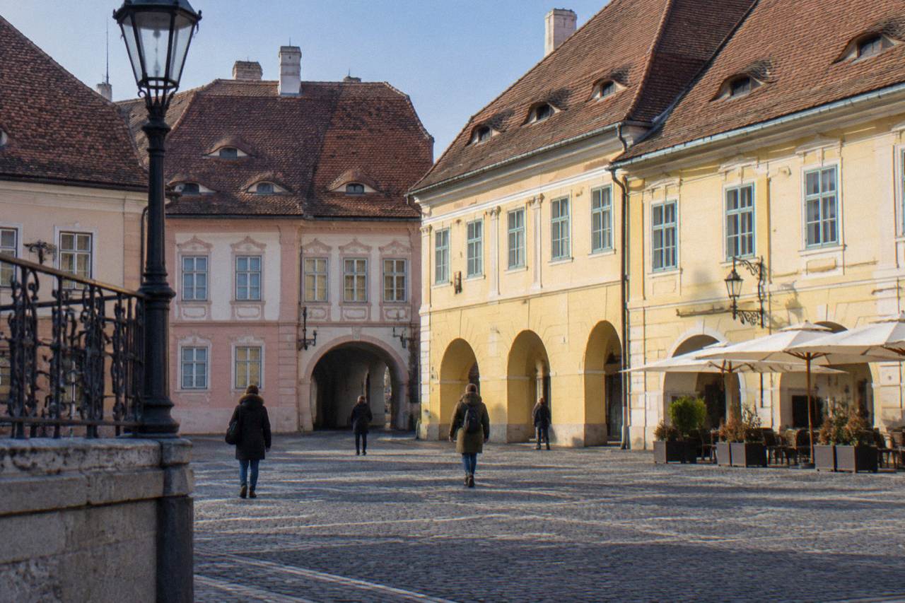 Pastel houses and cafe tables along a cobbled street in Sibiu's old town