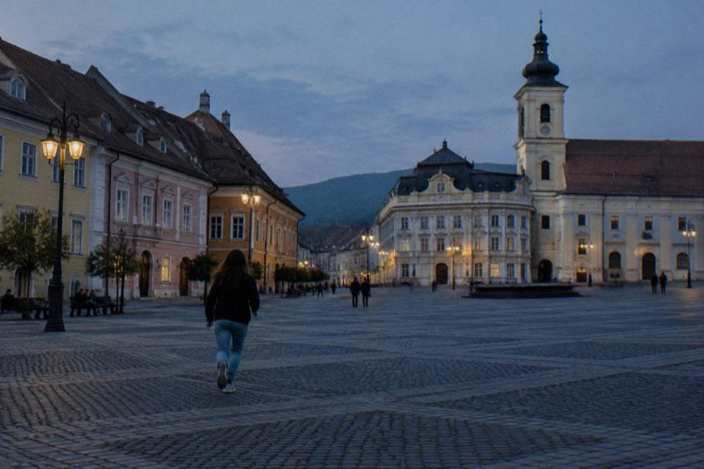 A winding mountain road climbing through green slopes toward a glacial lake