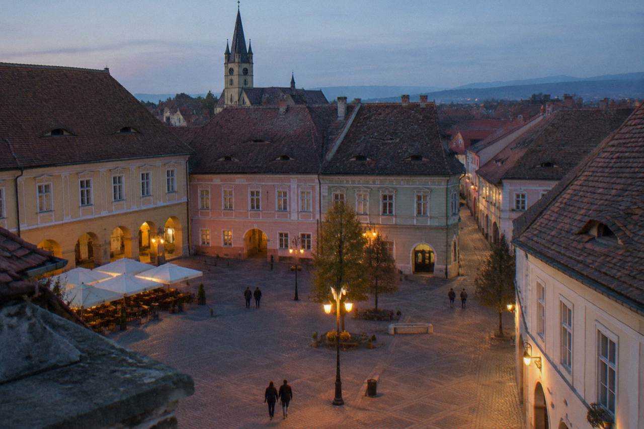 A quiet evening on a cobbled square in Sibiu's old town with medieval buildings lit by street lamps