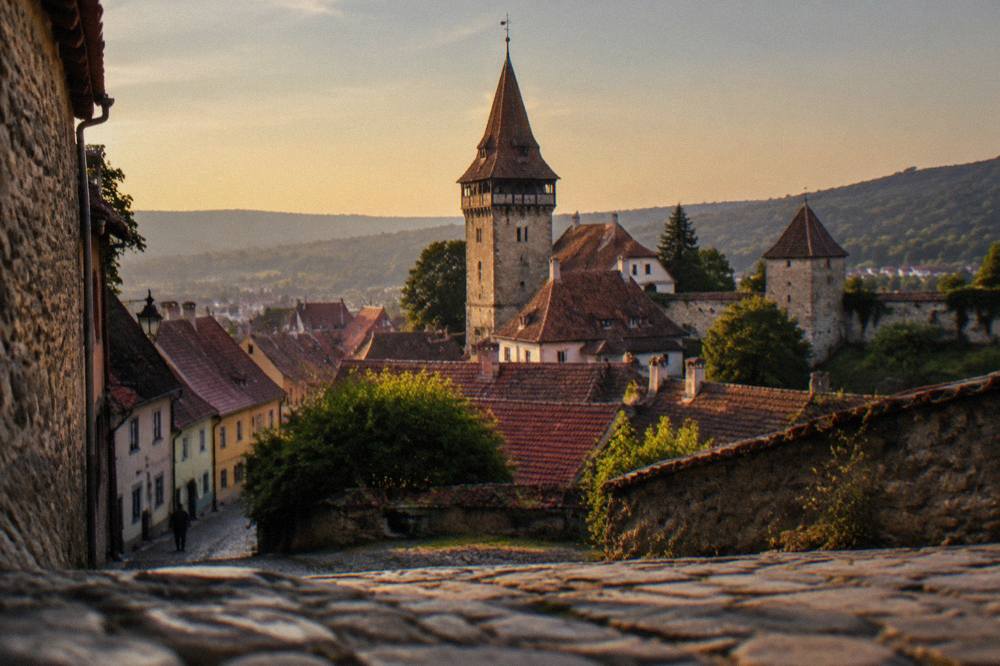 A stone clock tower rising above red tiled roofs inside the fortified citadel of Sighișoara