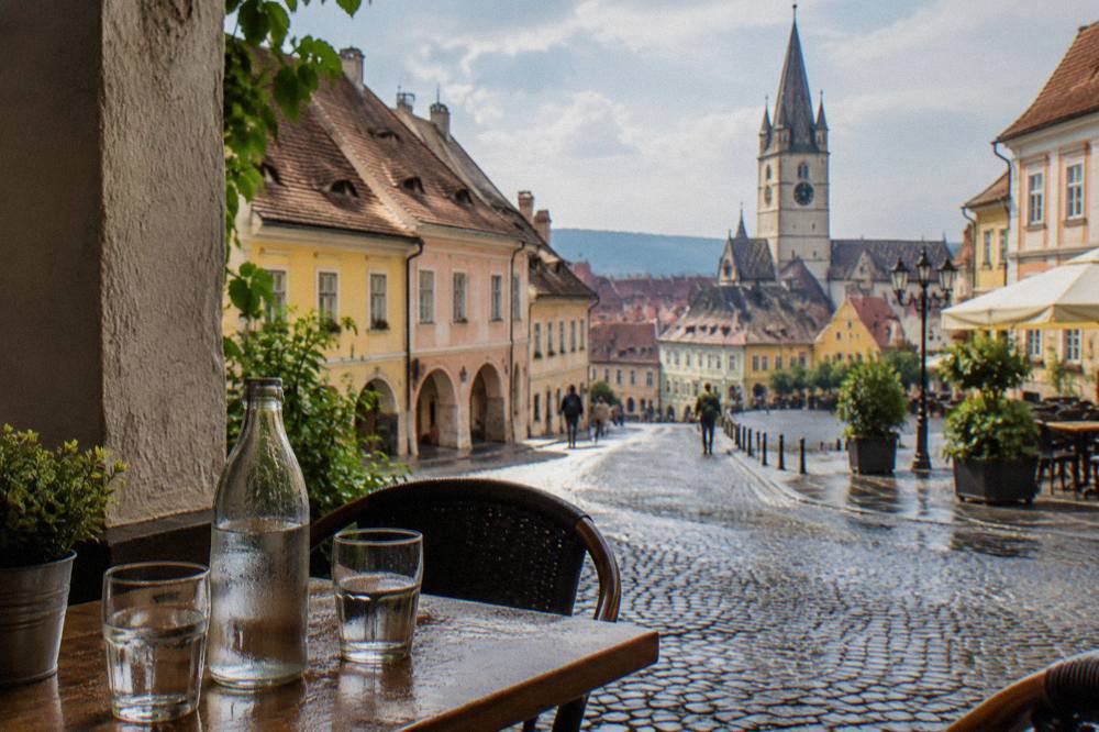 Bottled water and glasses on a cafe table beside a medieval street