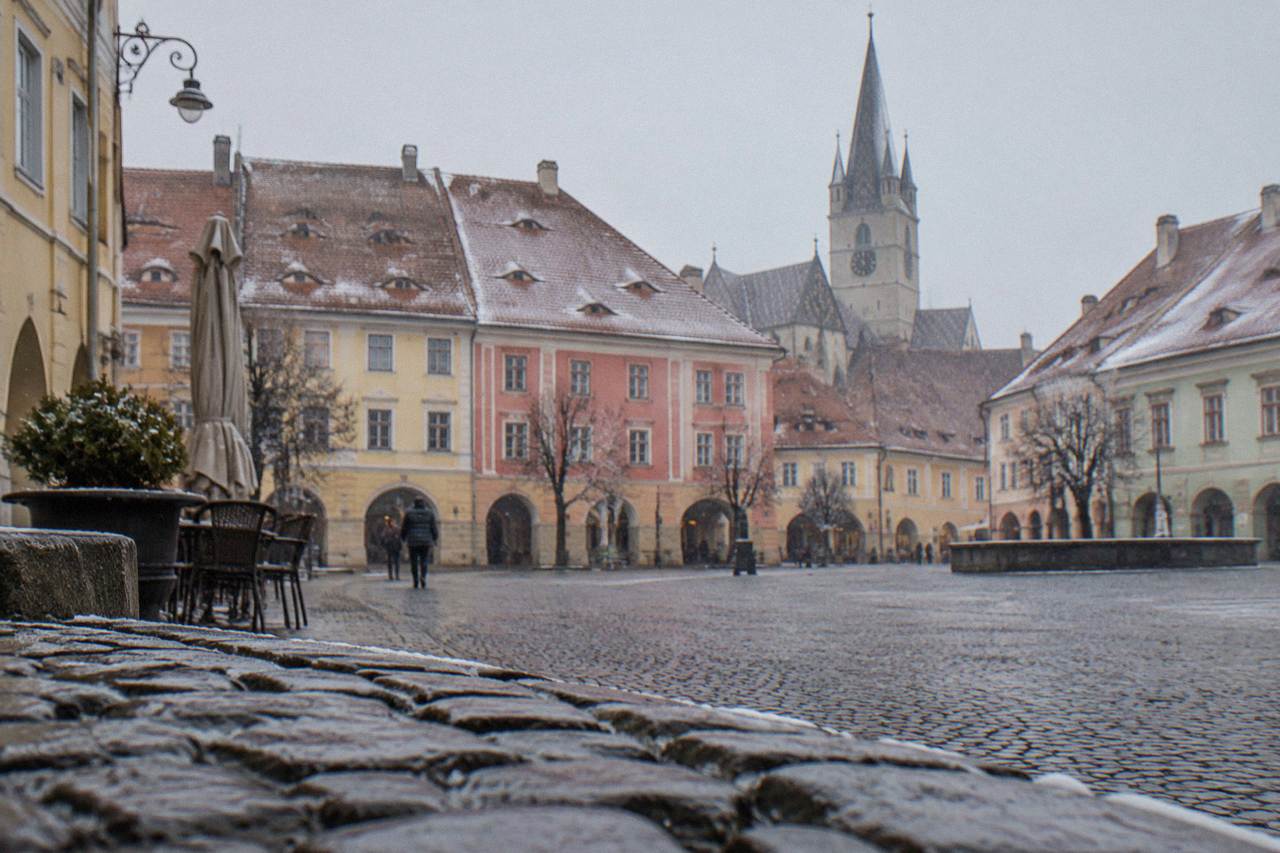 Colourful historic houses with tall pitched roofs around a square in a Transylvanian old town