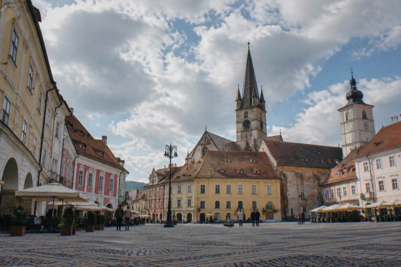 Colourful baroque and guild-era houses and church towers seen across a grand square in Sibiu