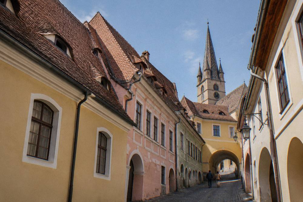 Steep tiled rooftops with small skylight windows looking down over a narrow old street in Sibiu