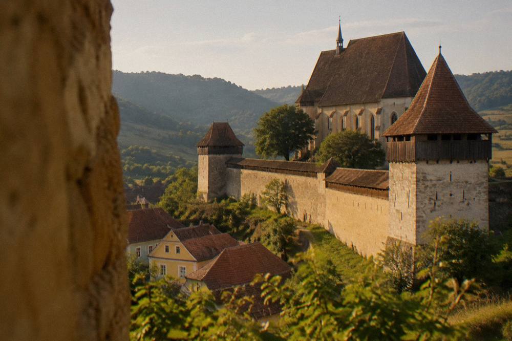 Close view of a church-fortress curtain wall with defensive towers in a green Transylvanian valley