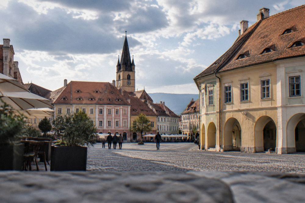 Traveller consulting a map at the edge of a boulevard in Sibiu with old buildings behind
