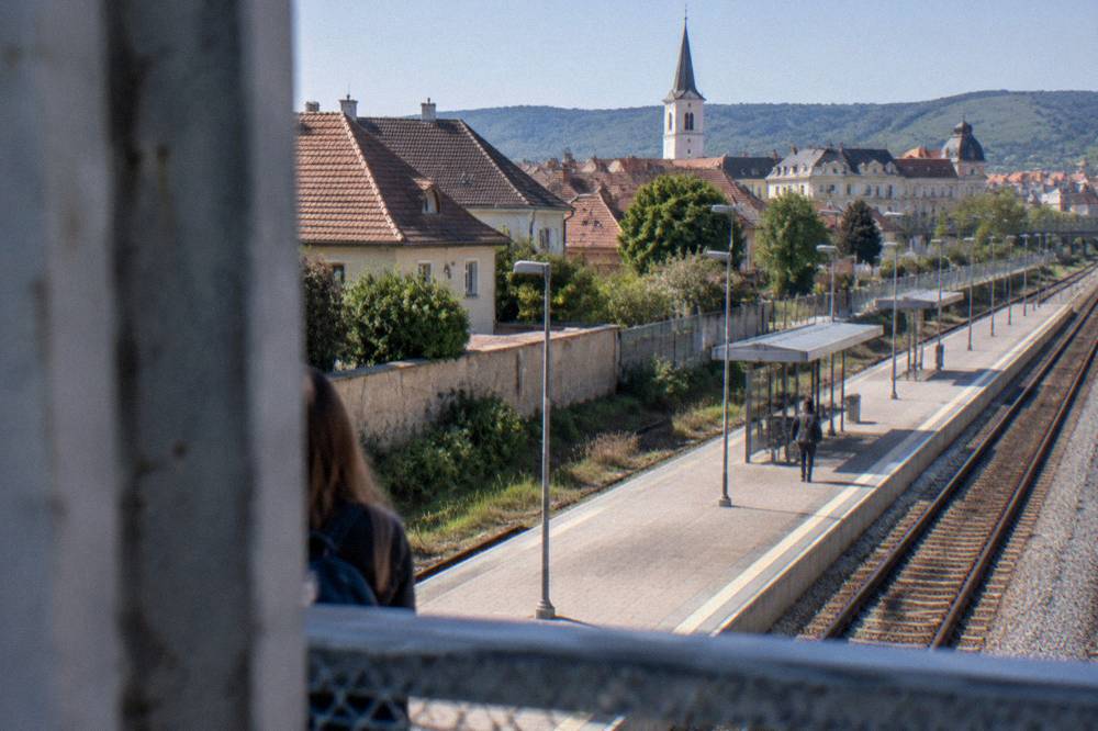 Railway line and platform seen from a footbridge near Turnișor with the city beyond