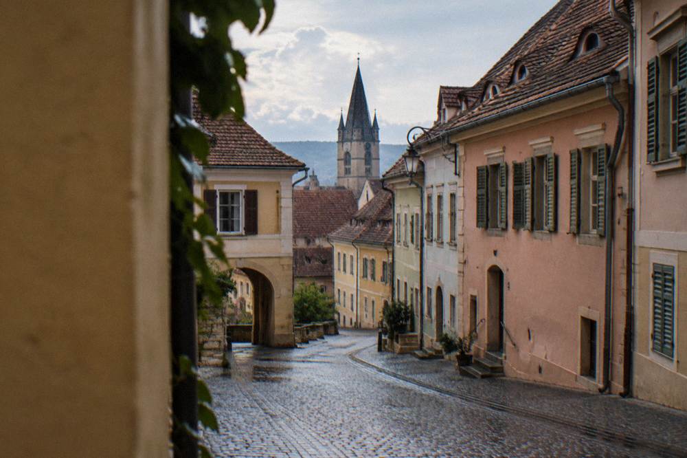 Calm cobbled street in the Rotarilor and station side of an old town, quiet houses and shutters, no people in focus.