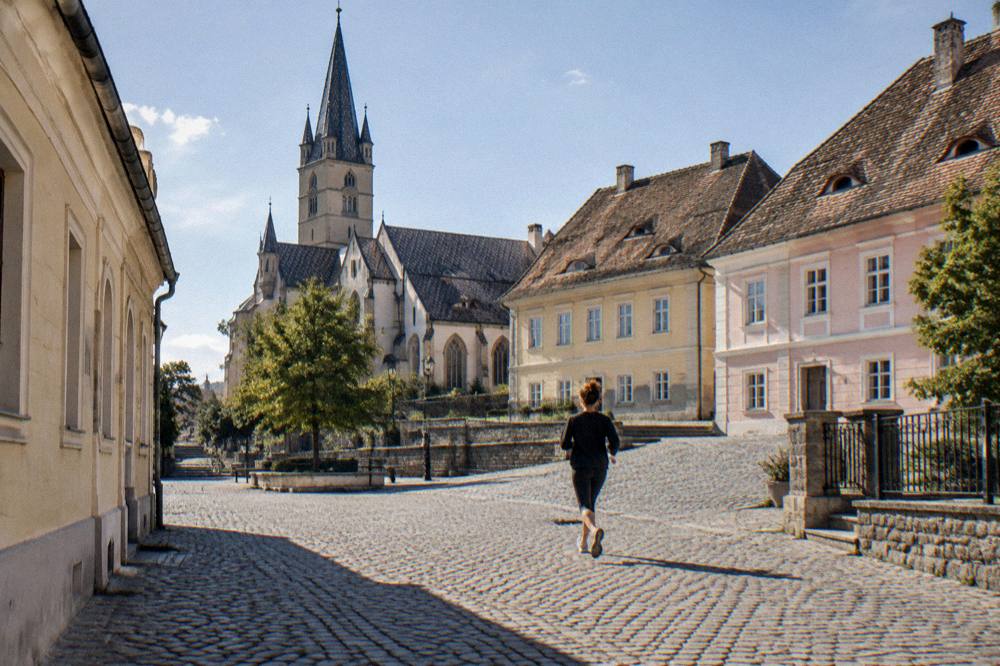 A small quiet square with a gothic church and old school buildings on a slight hill