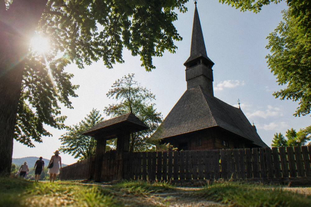 A wooden church and fence under summer greenery at the ASTRA Museum in Sibiu