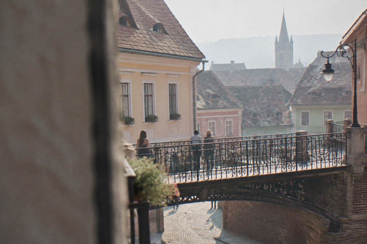 An old iron pedestrian bridge crossing a narrow lane between colourful historic houses in Sibiu