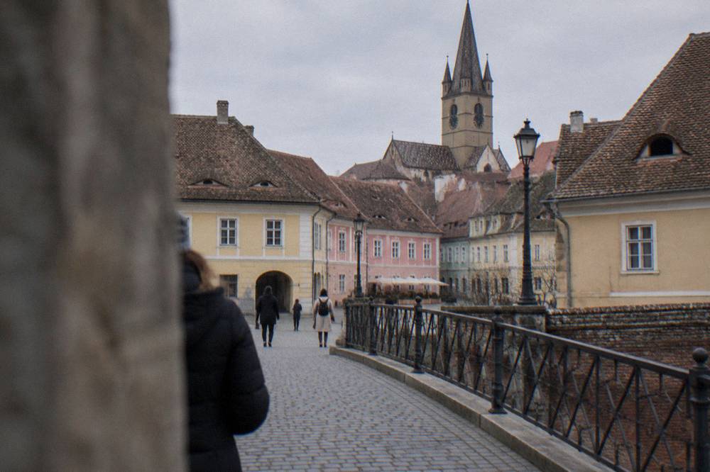 View across the Bridge of Lies toward the pastel facades of Piața Mică in Sibiu