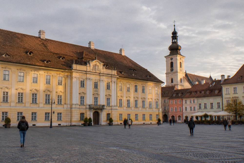 Cobblestone square with colourful townhouses and church tower at golden hour