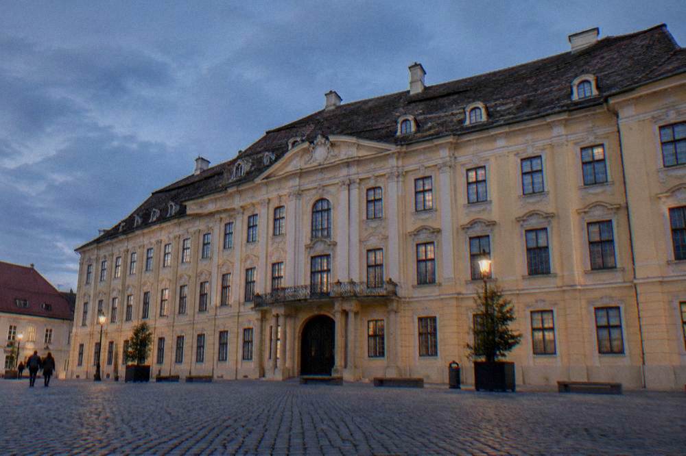 The facade of a Baroque palace on a town square, seen from across the cobbles.