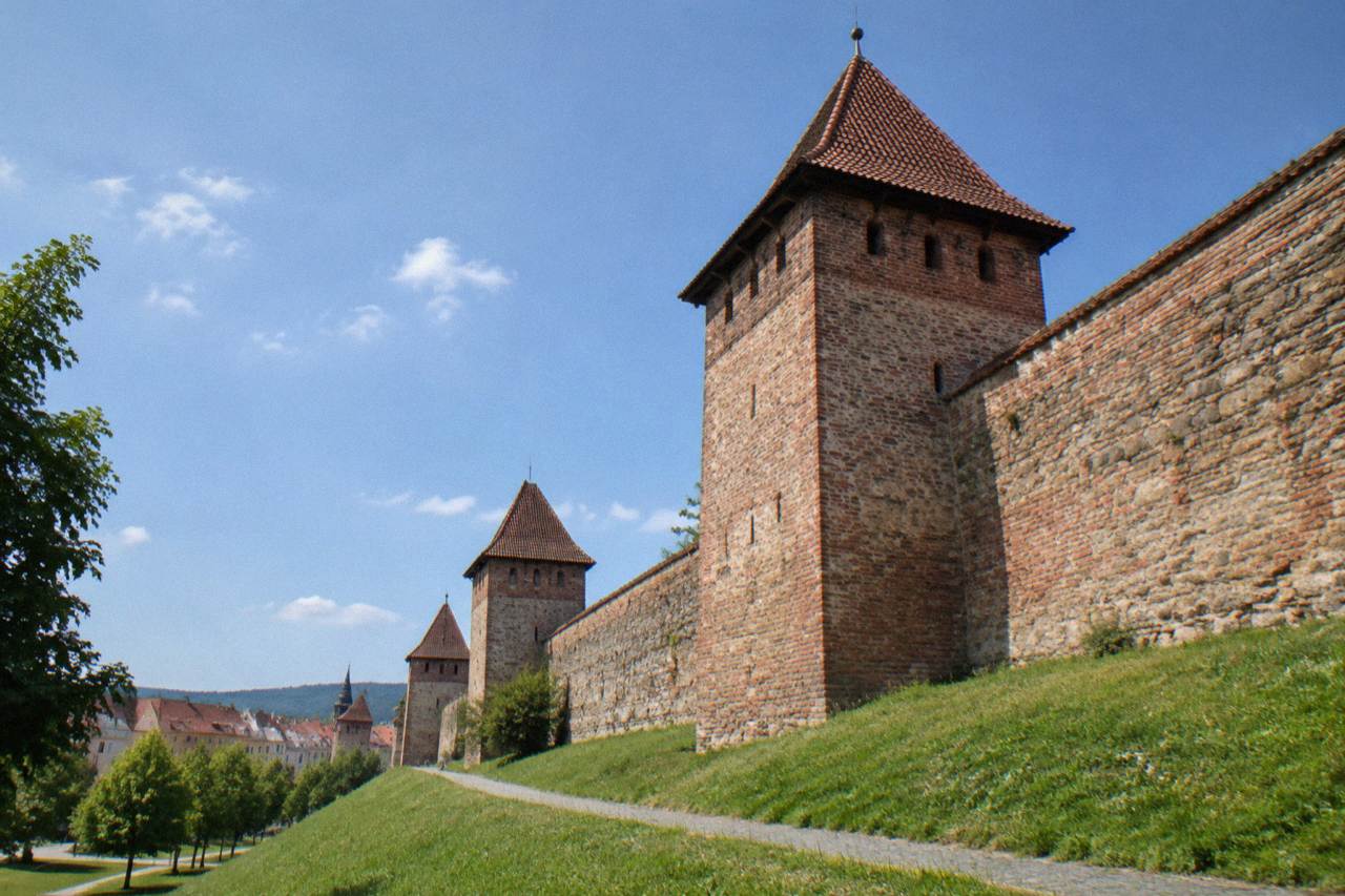 Medieval brick towers of the Sibiu city wall seen from a green lawn below the old town