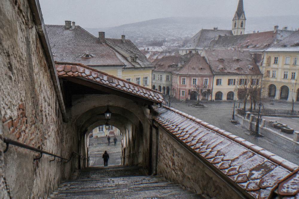 A covered stone staircase passage descending between old walls in Sibiu