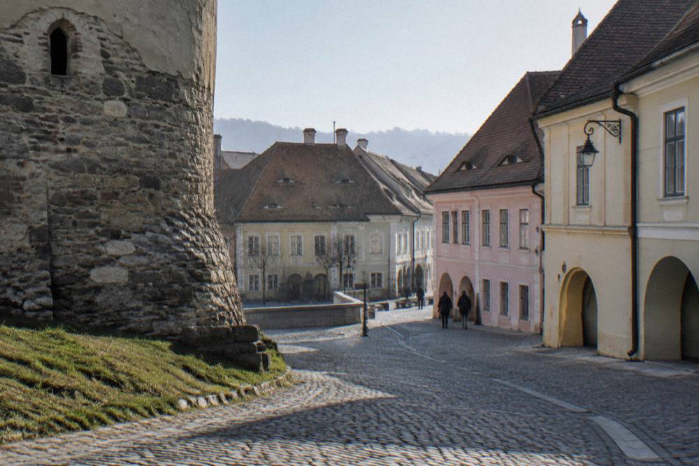 Weathered stone foundation of a Sibiu defensive tower with grass at its base