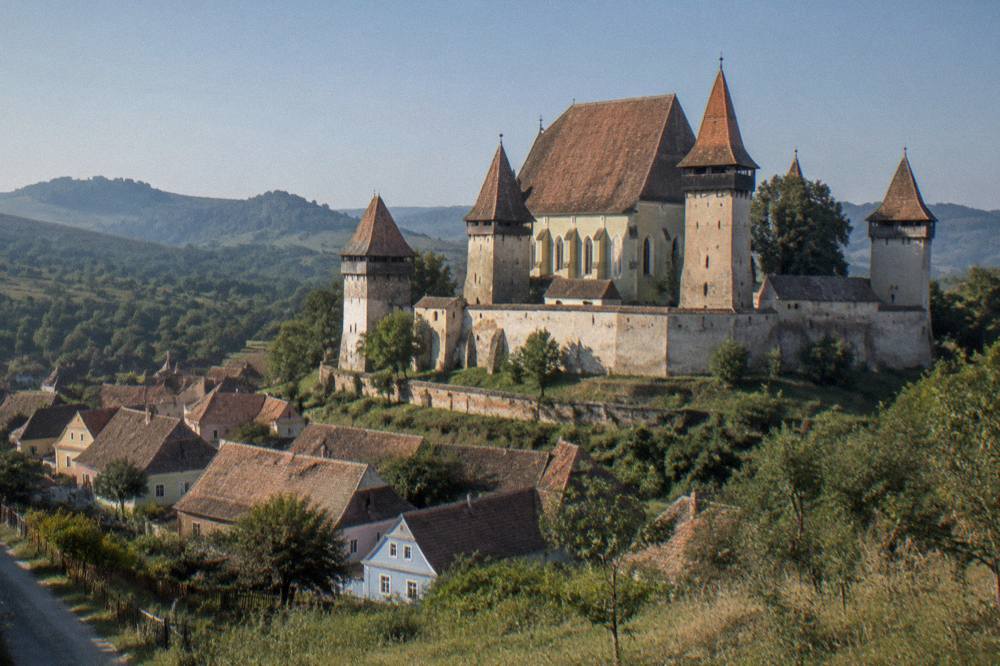 A fortified church with high defensive walls in a Transylvanian village landscape