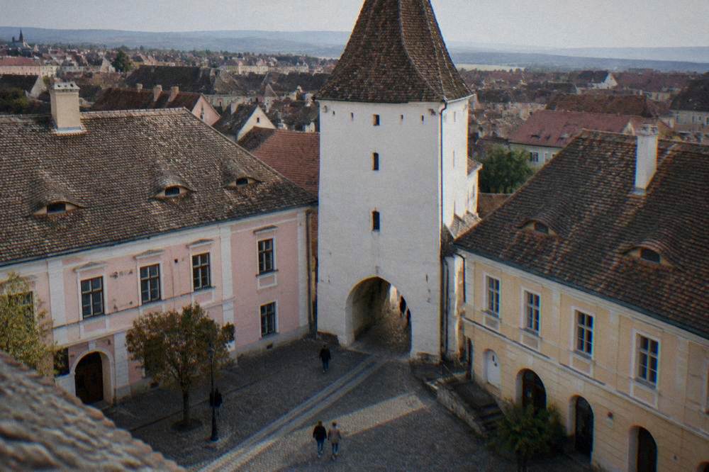 Scaffolding climbs a white medieval tower rising above a cobbled square.
