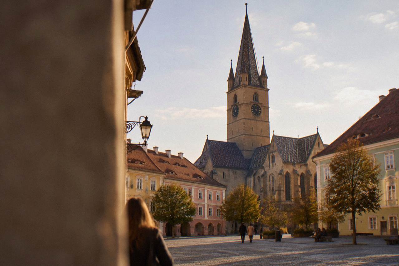 Gothic church tower rising above the colourful historic buildings of a Transylvanian square