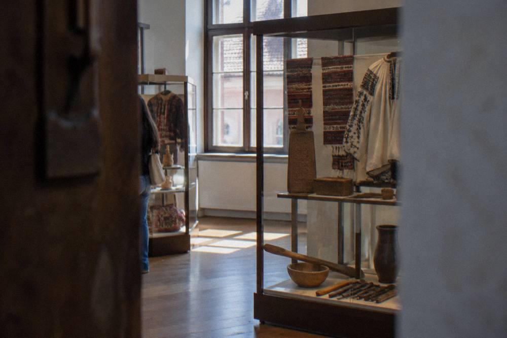 Close view of ethnographic display cases with textiles, tools and carved objects arranged on shelves