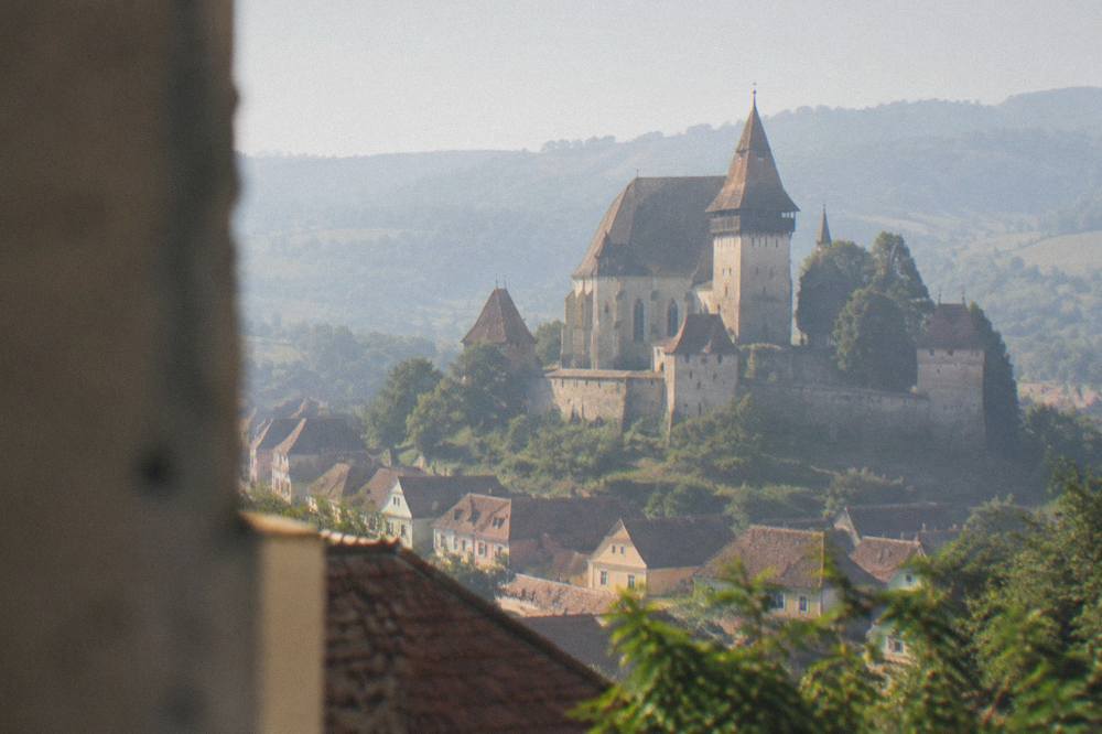 A fortified church tower rising above village houses in the Transylvanian countryside