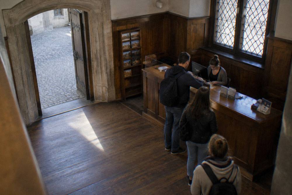 A museum ticket desk in a wood-panelled room with a stone doorway