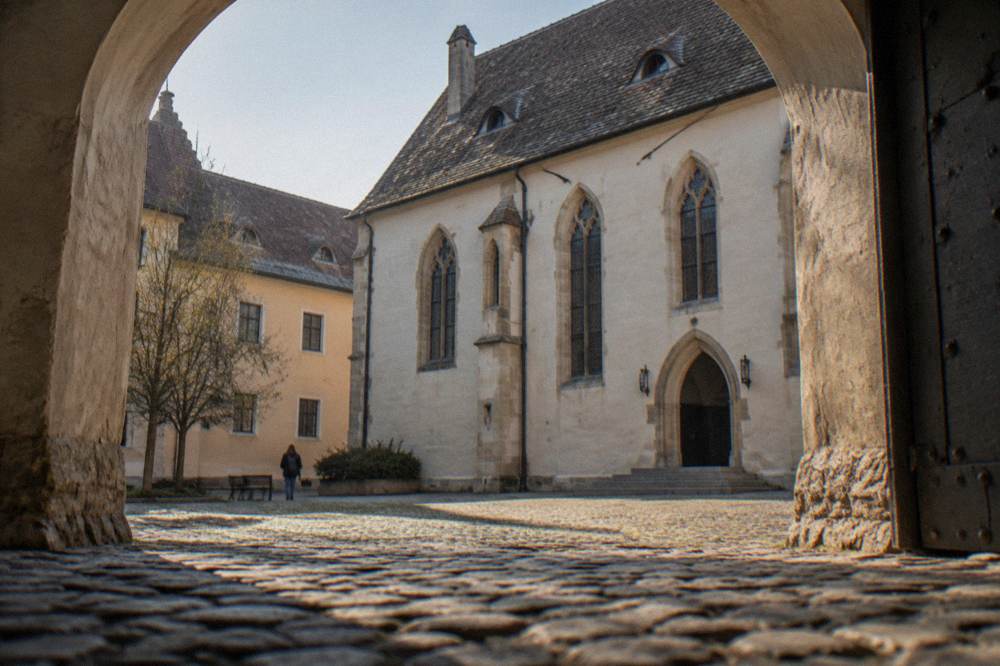 A stone courtyard of a museum building seen through an arched gateway