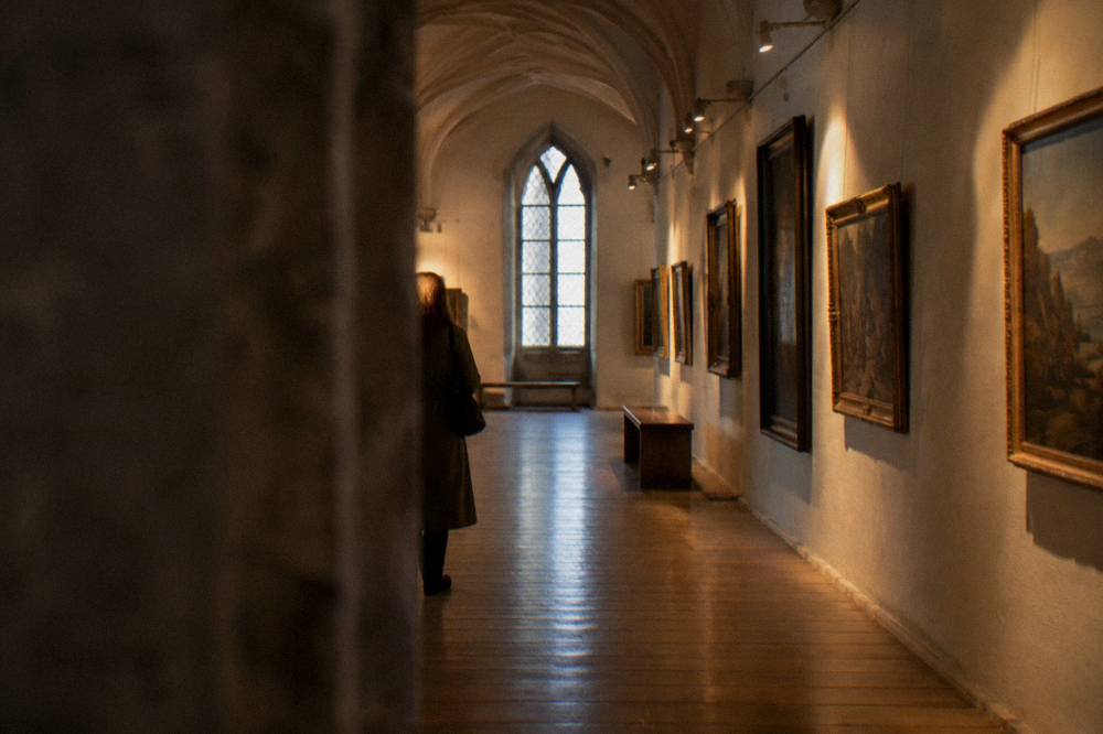 A long gallery hall with framed paintings and wooden floors