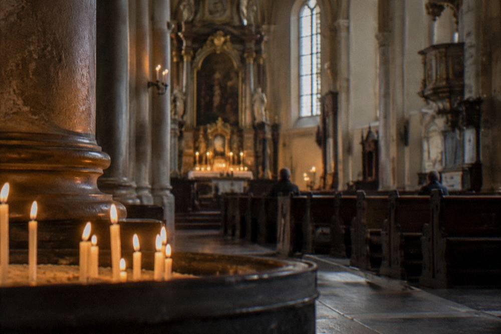 Candles lit inside a quiet church interior with stone columns