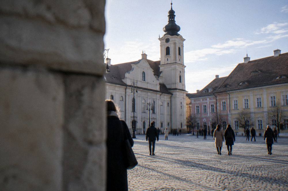 A pedestrian square in a Transylvanian city with people walking past historic facades