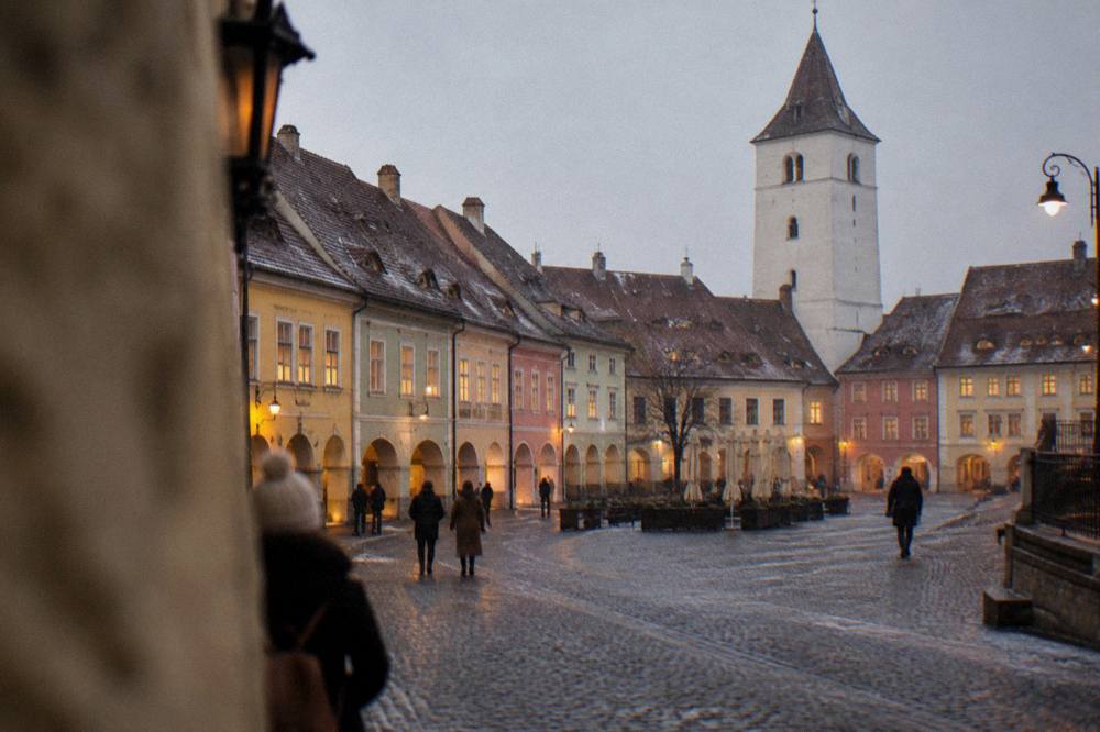 The small square of a Transylvanian old town at dusk with warm window light