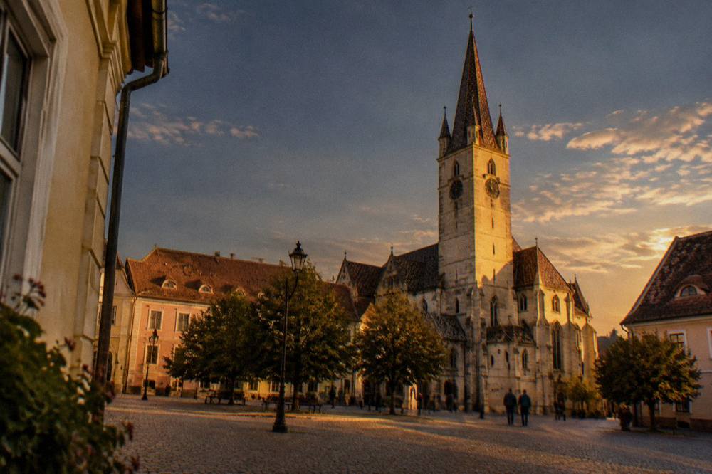 Illuminated Gothic tower of the cathedral seen against a darkening evening sky over the square