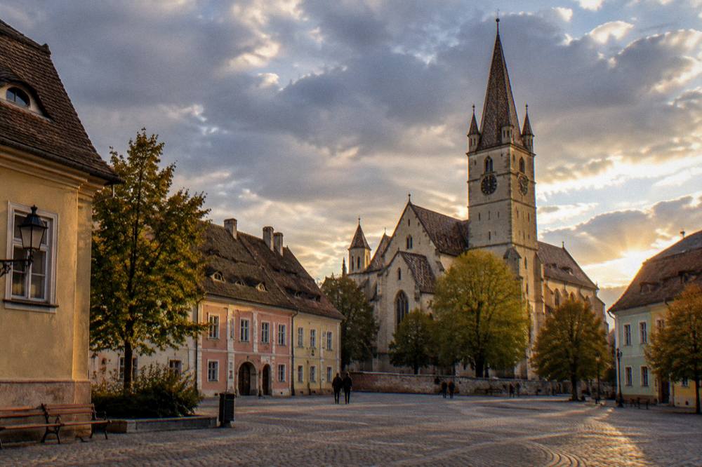 Evening view across Huet Square with warm light on the historic facades and the church tower above