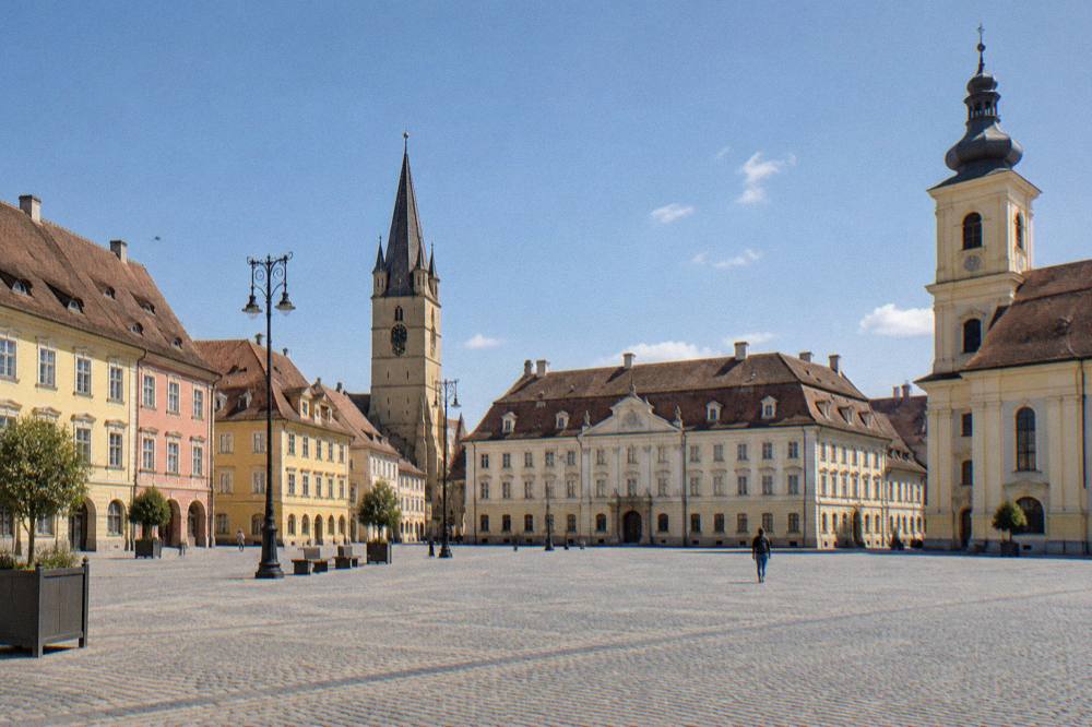 Morning light on an empty cobbled square with a gothic tower and old merchant houses