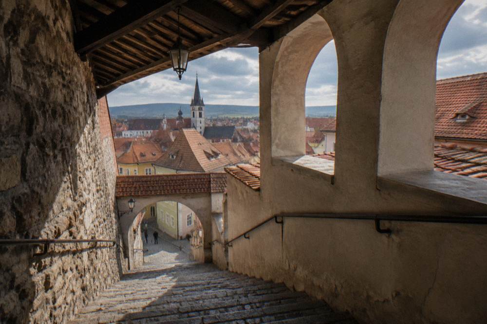 A covered stone stairway descending between old walls in Sibiu
