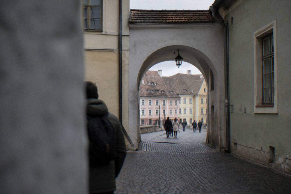 Visitors walking through an arched passage between old houses in central Sibiu