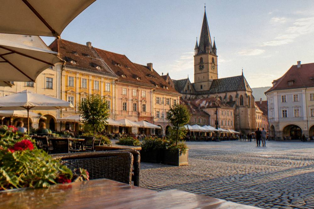 Evening light on the painted facades and terraces of a historic square in Sibiu