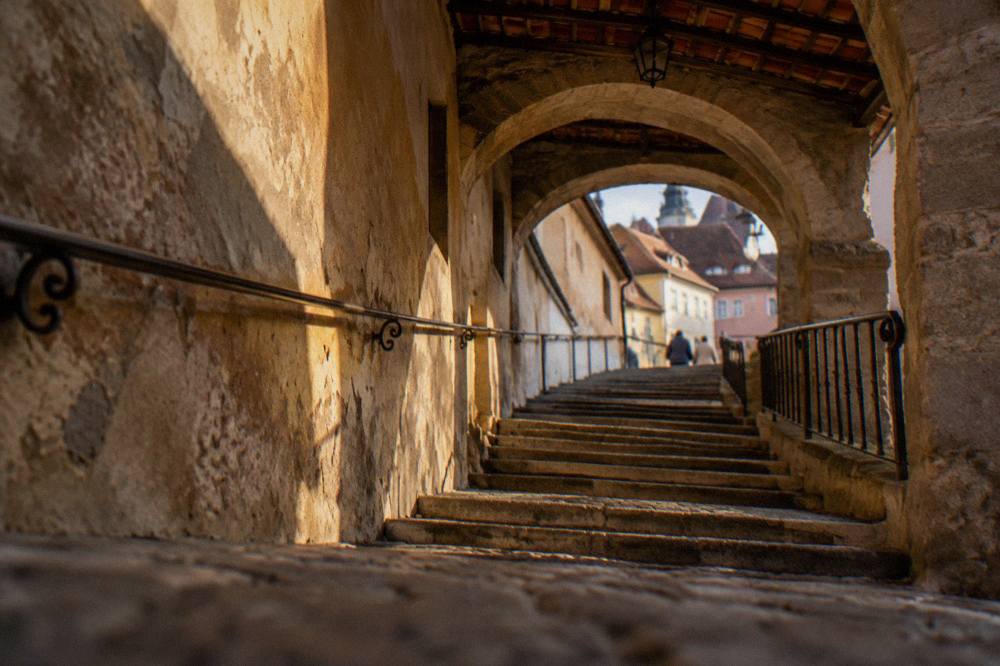 Steps of the passage curving upward under arches with wrought iron railings