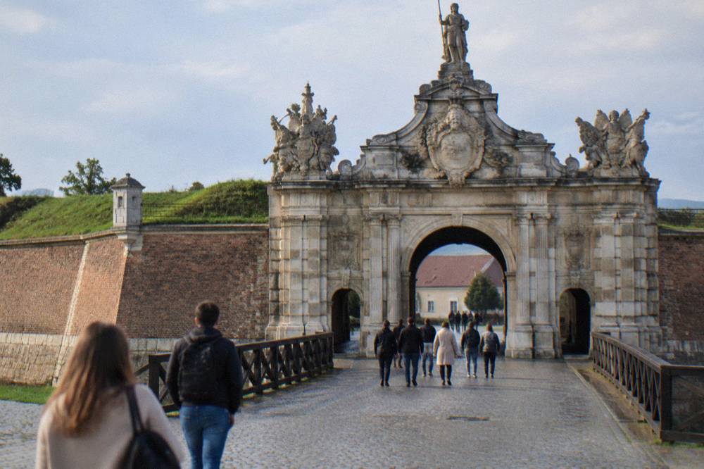 Visitors walking through the ornate ceremonial gate of the Alba Carolina citadel