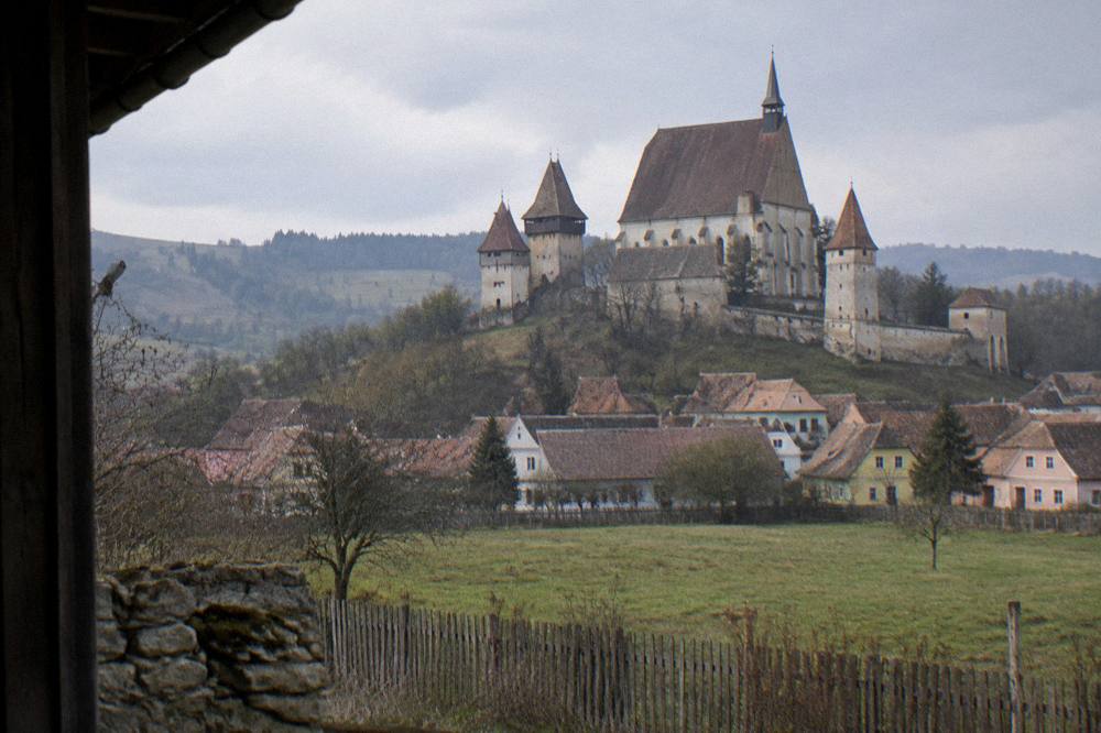 A fortified church with high defensive walls in a Transylvanian village meadow