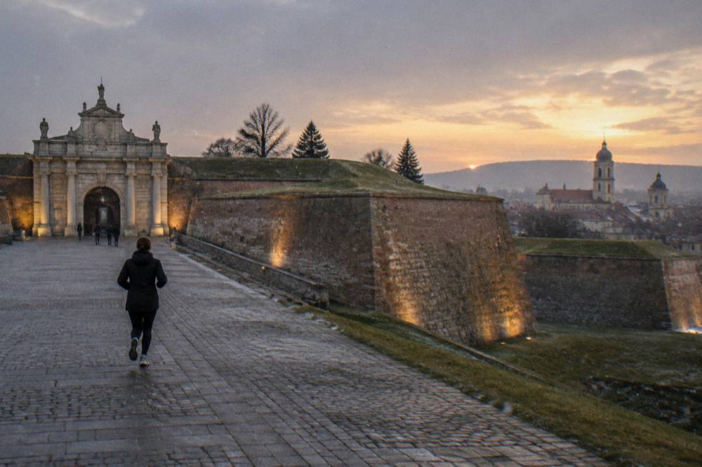A star fortress at dusk with warm light on the bastion walls and a town beyond