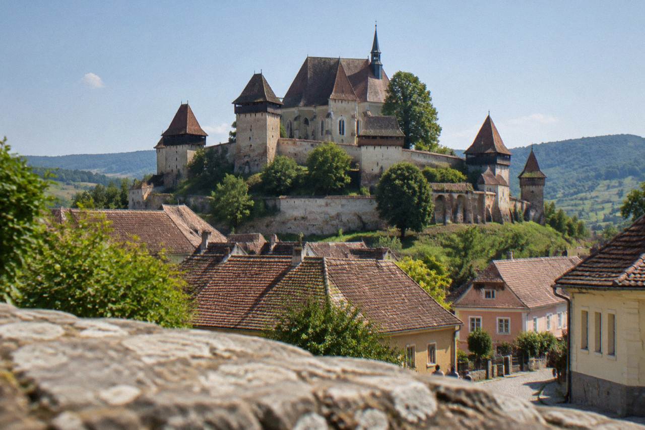 Fortified church on a hill above red-roofed village houses in Transylvania