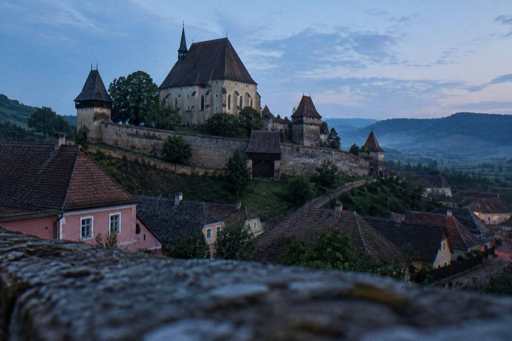 Thick stone defensive wall with wooden gate and towers surrounding a church